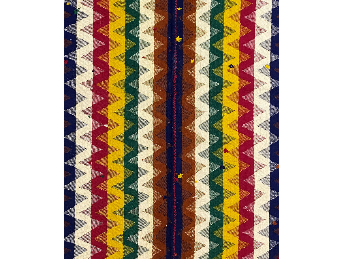 Vista aproximada de um tapete Jajim: riscas verticais em ziguezague em azul, vermelho, amarelo e creme