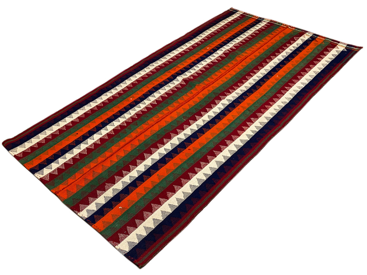Tapete Jajim disposto no chão: padrão de riscas diagonais em verde, vermelho, azul e creme