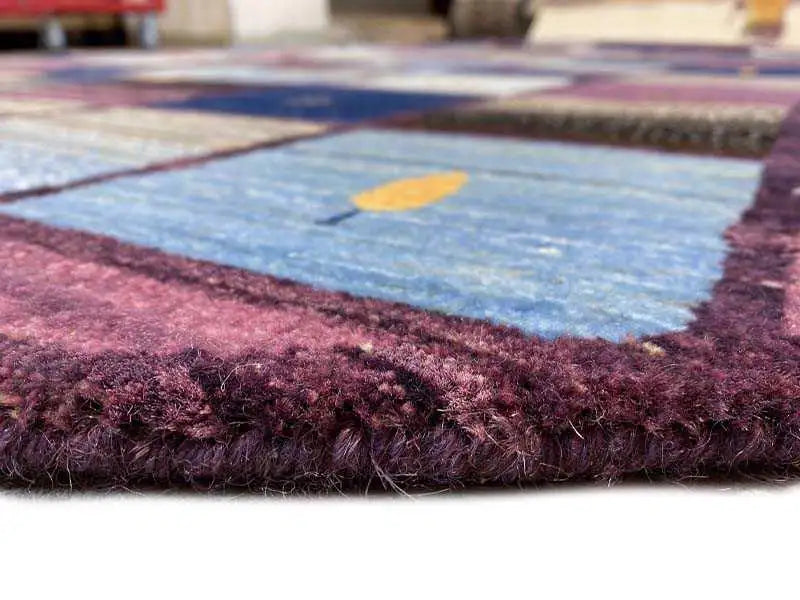 Pormenor da borda de um tapete Gabbeh com pelo denso em tons de violeta e bordeaux