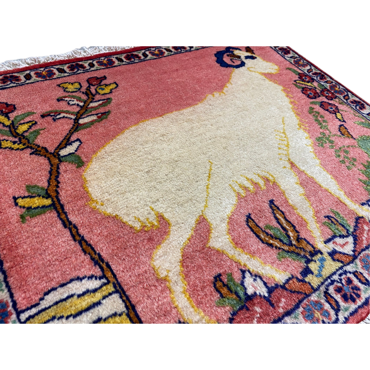 Close-up of carpet: soft pile with animal motif, red-beige colour gradient, colourful ornaments