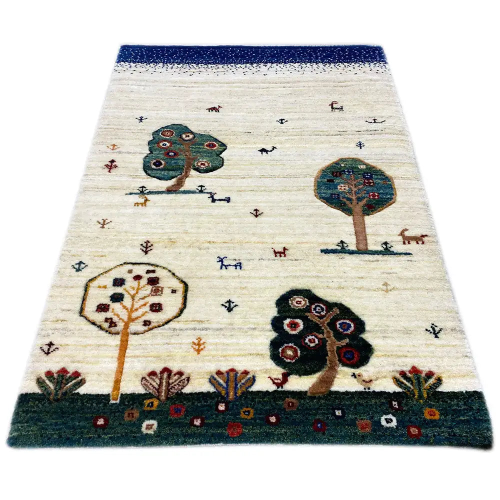 Tapete Gabbeh, de cor creme, com rebordo azul e motivos de árvores/animais no padrão