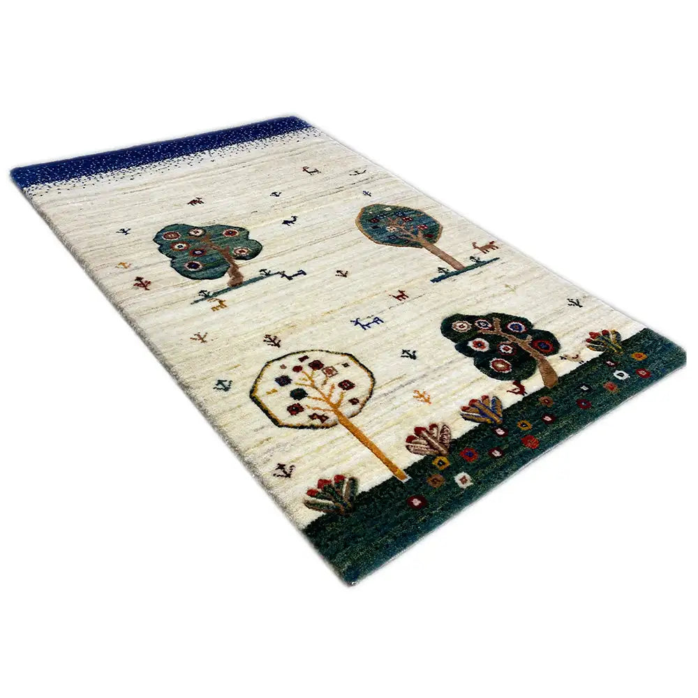 Tapete Gabbeh com borda azul, cor de fundo creme e motivos coloridos de árvores e animais