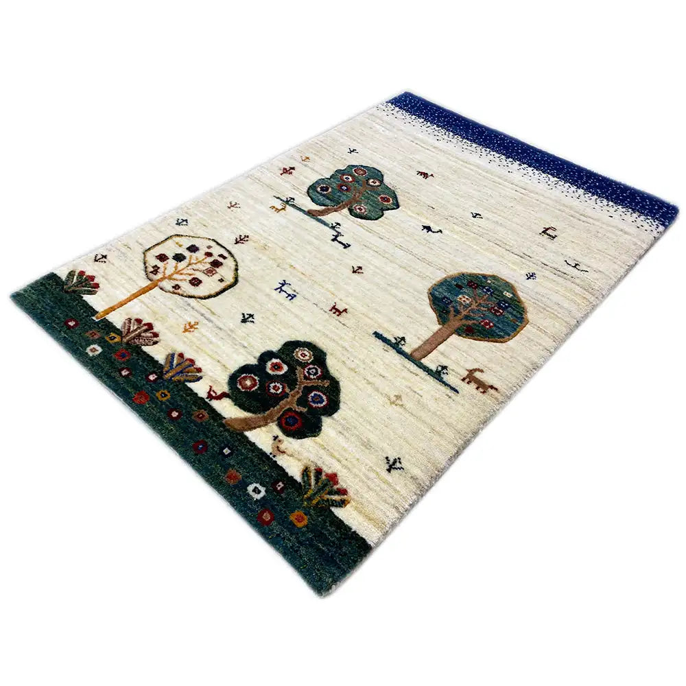 Tapete Gabbeh em vista diagonal: base creme, acabamento azul, motivos de árvores e flores