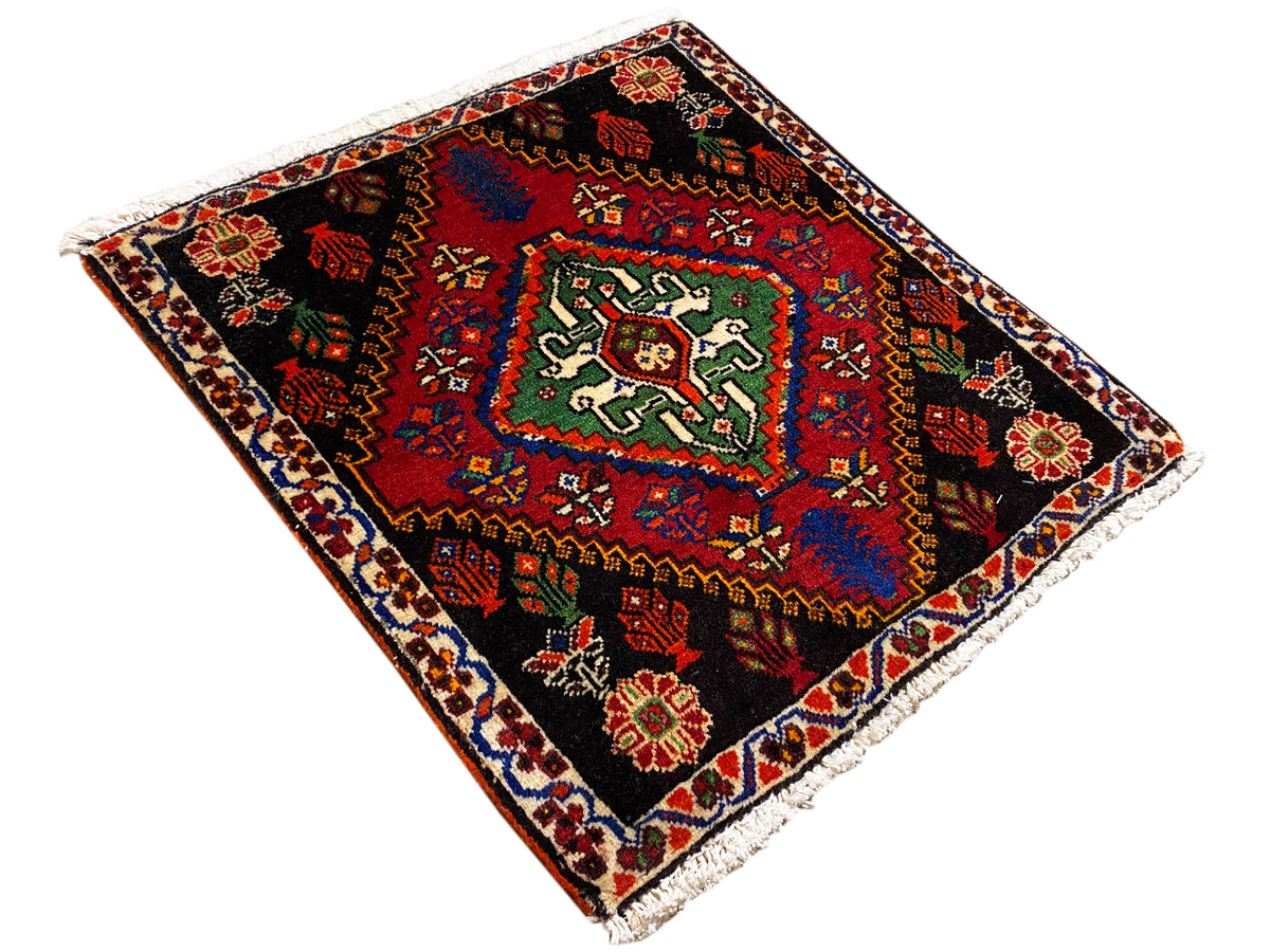 Tapete Poshti 56x56 cm, colocado na diagonal, com ornamentos geométricos em vermelho, verde e azul