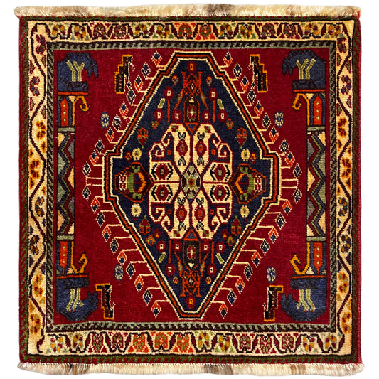 Tapete Poshti (59×61 cm) com padrão vermelho, bordaduras multicoloridas e franjas