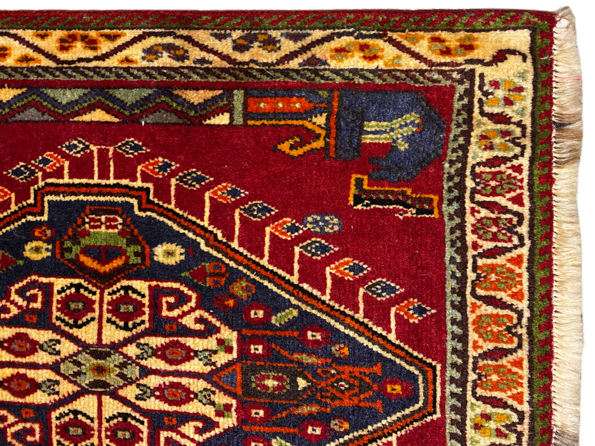 Pormenor do tapete Poshti (59×61 cm): campo vermelho com motivos ornamentais de tapete e rebordo contornado
