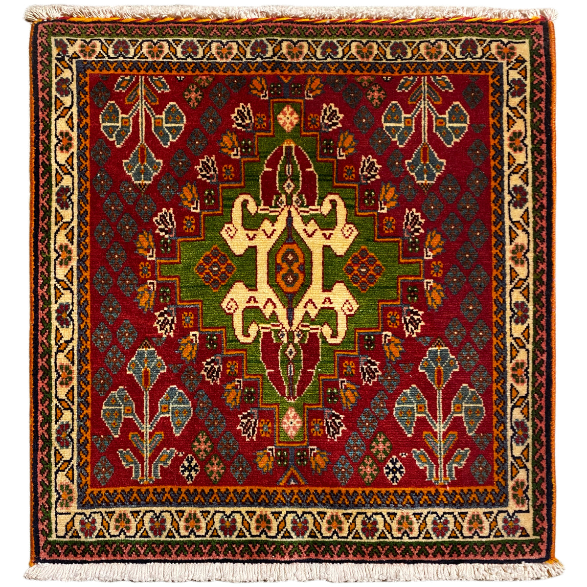 Tapete oriental com padrão quadrado em tons fortes de vermelho, verde e bege, com franjas