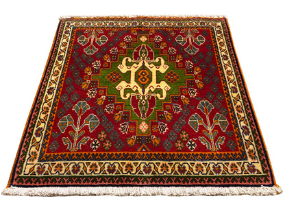 Tapete oriental com motivo central vermelho, detalhes verdes e borda bege, com franjas