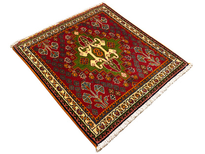 Tapete oriental vermelho com ornamentos de cruzes e arabescos, apontamentos verdes e borda decorativa