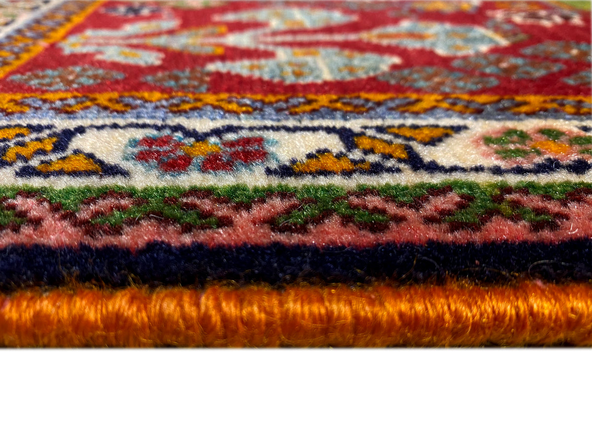 Borda do tapete em detalhe: pelo denso com fundo vermelho e ornamentos coloridos