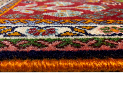 Borda do tapete em detalhe: pelo denso com fundo vermelho e ornamentos coloridos
