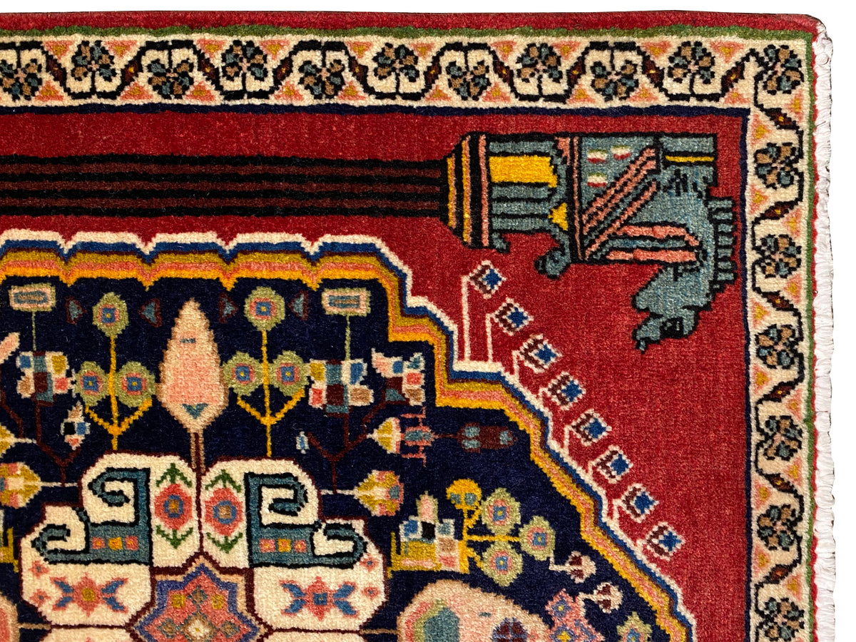 Pormenor do tapete Poshti: borda vermelha com motivos decorativos nos cantos e faixas ornamentais