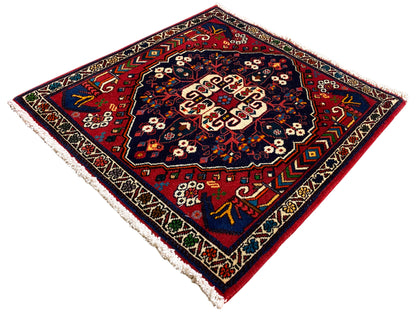 Tapete quadrado com ornamento colorido, superfície azul-escura, motivos de borda, franjas