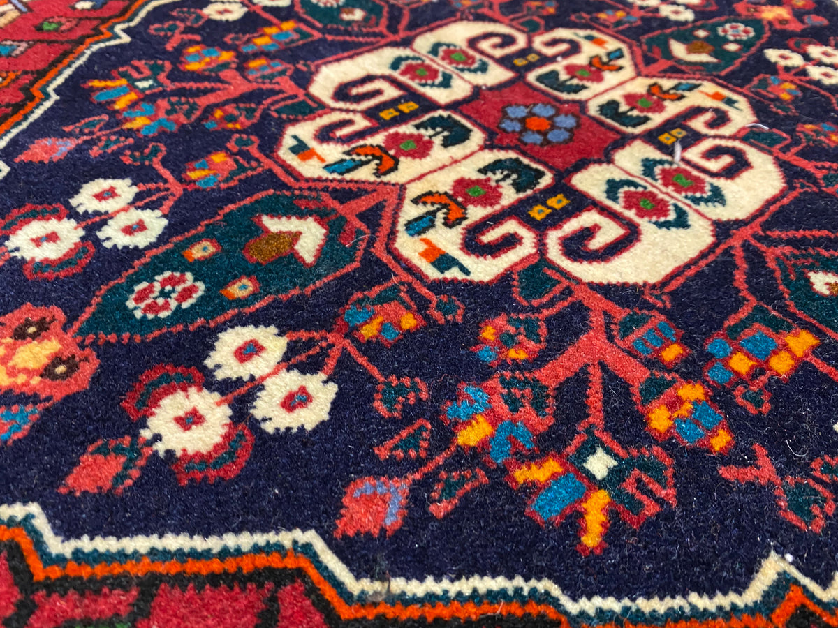 Vista aproximada do pelo do tapete com ornamentação colorida em azul, vermelho, creme e verde