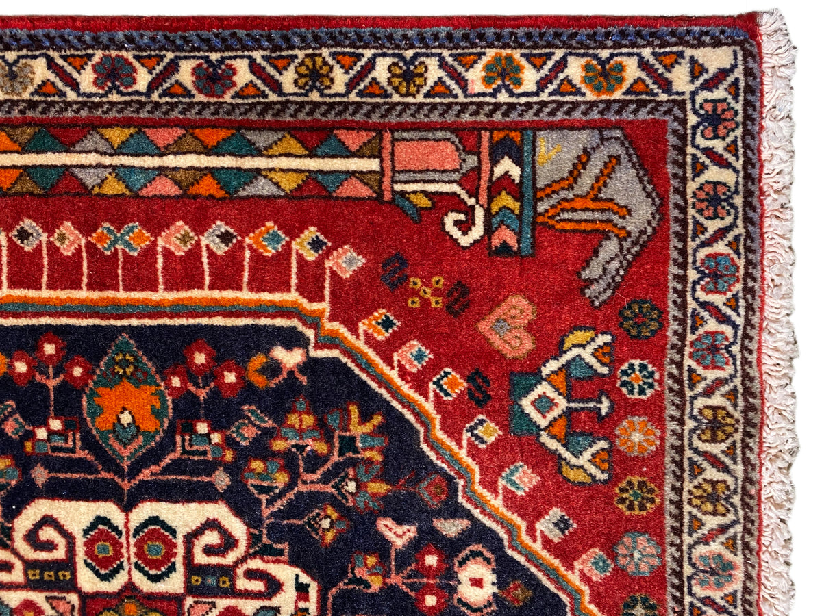 Detalhe do tapete: campo ornamental vermelho e azul com borda multicolorida e franjas