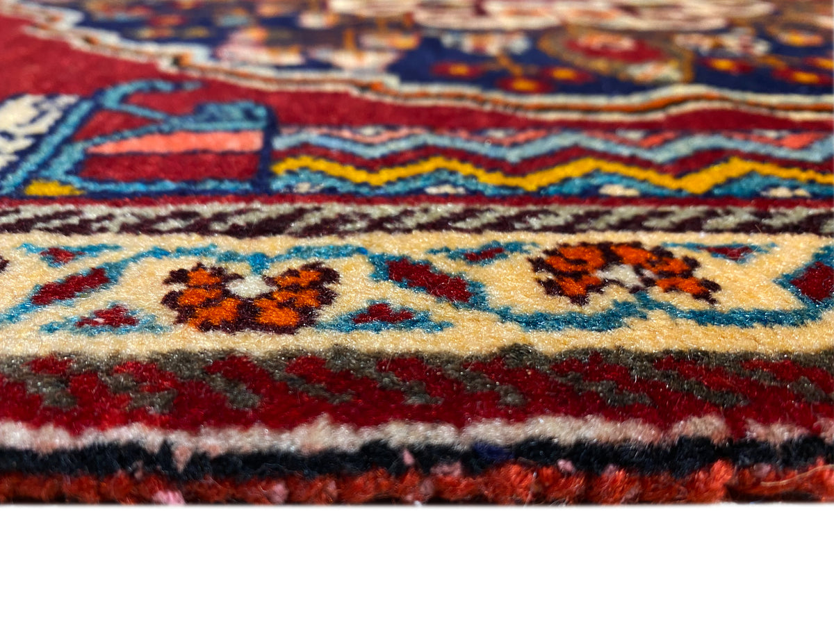 Pormenor de perto de um tapete: cercadura colorida, ornamentos multicoloridos e textura de pelo espessa