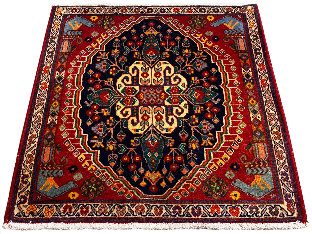 Tapete quadrado de 67x60 cm com padrão centrado em azul-escuro, vermelho e amarelo