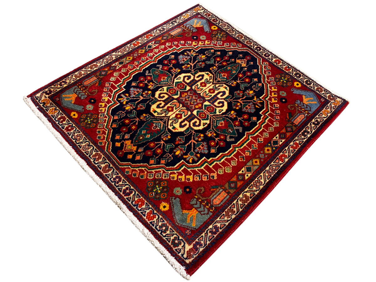 Tapete quadrado de 67x60 cm, campo vermelho com bordadura azul-escura e detalhes amarelo-dourados