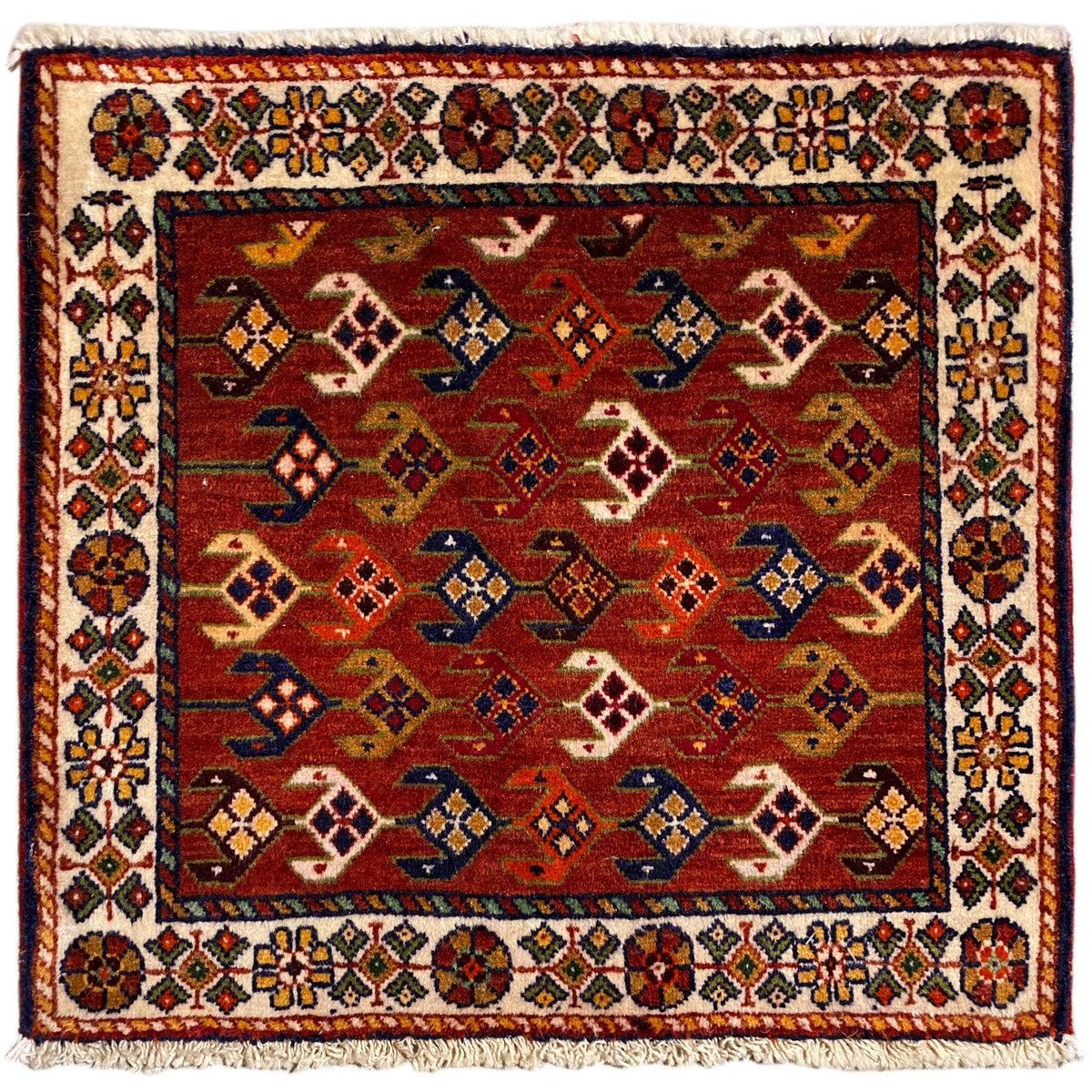 Tapete quadrado com fundo vermelho, bordadura branca multicolorida e franjas