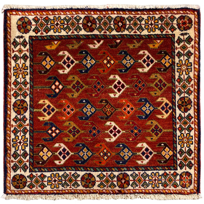 Tapete quadrado com fundo vermelho, bordadura branca multicolorida e franjas