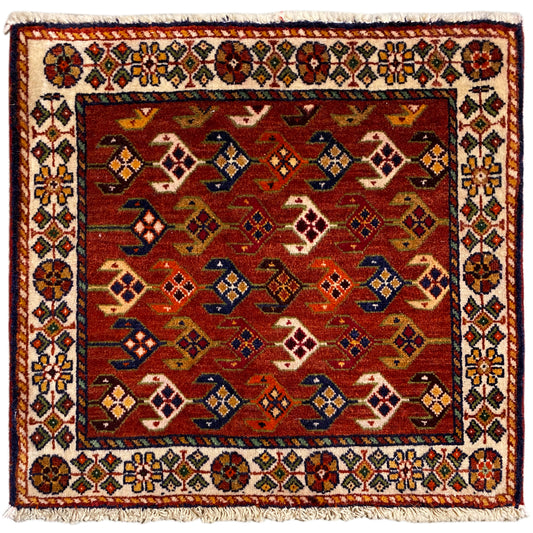 Tapete quadrado com fundo vermelho, bordadura branca multicolorida e franjas