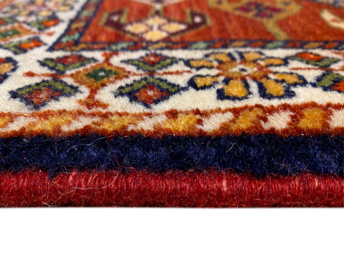 Orla de tapete com pelo vermelho, rebordo escuro e faixa com padrão ornamental