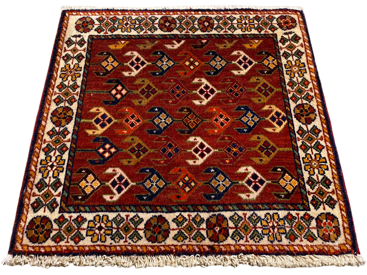 Tapete com fundo vermelho, área com padrão multicolorido e cercadura, franjas na borda