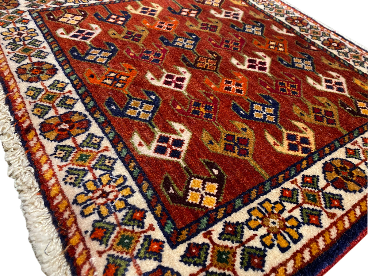 Tapete com campo de padrão vermelho, moldura azul-turquesa e rebordo desfiado
