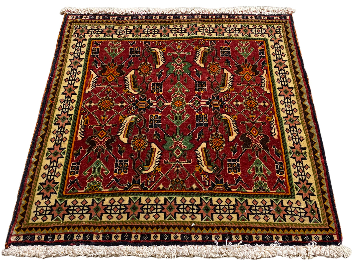 Tapete Poshti 63x61 cm, vista oblíqua: padrão ornamental vermelho em verde e bege.