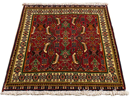 Tapete Poshti 63x61 cm, vista oblíqua: padrão ornamental vermelho em verde e bege.