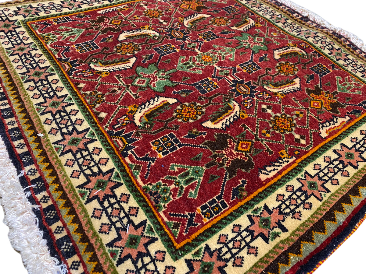 Tapete Poshti 63x61 cm, vista detalhada: padrão vermelho com motivos de animais/ornamentos e bordadura.