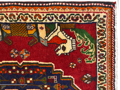 Grande plano de um tapete Poshti, campo vermelho com animais, contorno decorativo azul e bordadura com padrão