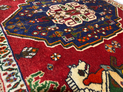 Pormenor de um tapete Poshti, campo vermelho com uma coroa ornamental azul e motivos de animais