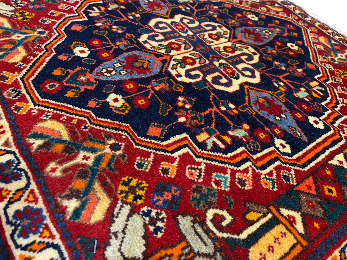Grande plano de um tapete: padrão azul com ornamentos vermelhos e amarelos, textura tecida