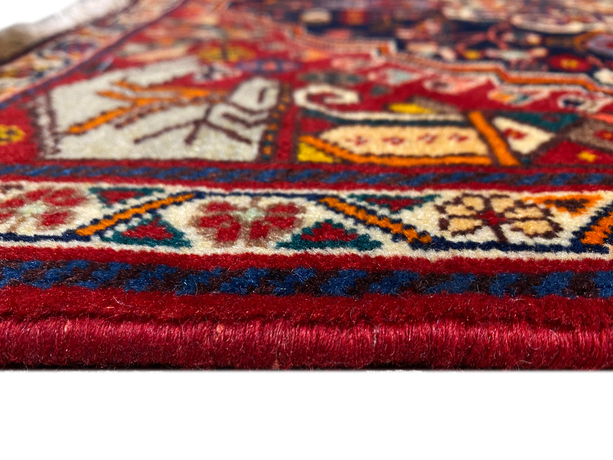 Detalhe do tapete na bainha: bordadura vermelha e azul, padrões multicolores e franjas curtas