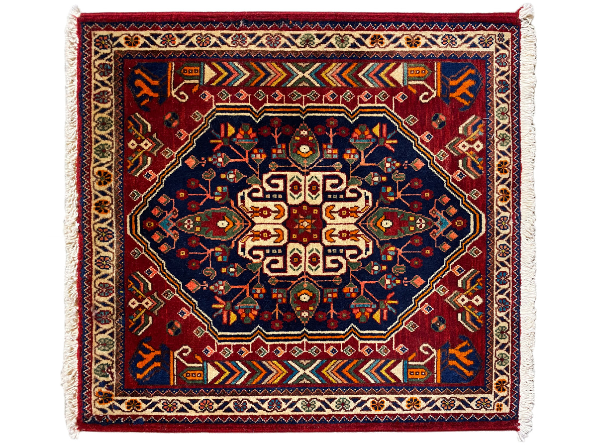 Tapete 63x60 cm em azul-escuro com padrão vermelho, faixa de contorno e franjas
