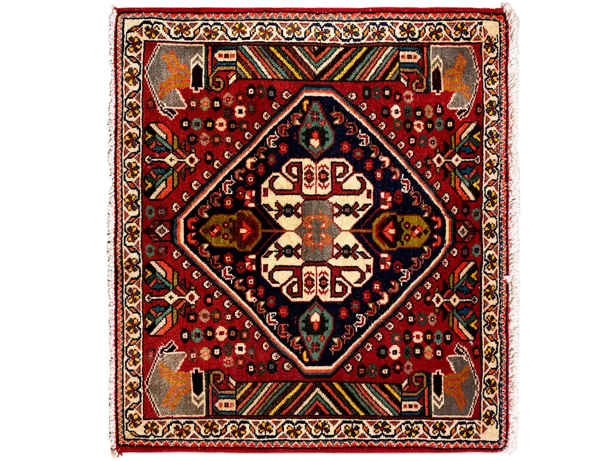 Tapete oriental com fundo vermelho, medalhão azul-escuro e ornamentos geométricos