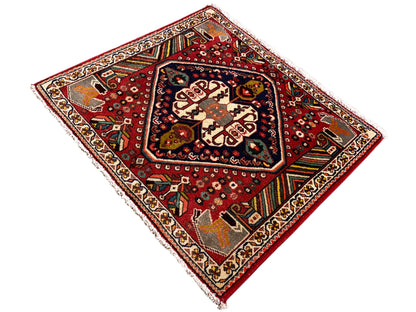 Tapete oriental com fundo vermelho, formas de cor creme e faixas decorativas coloridas