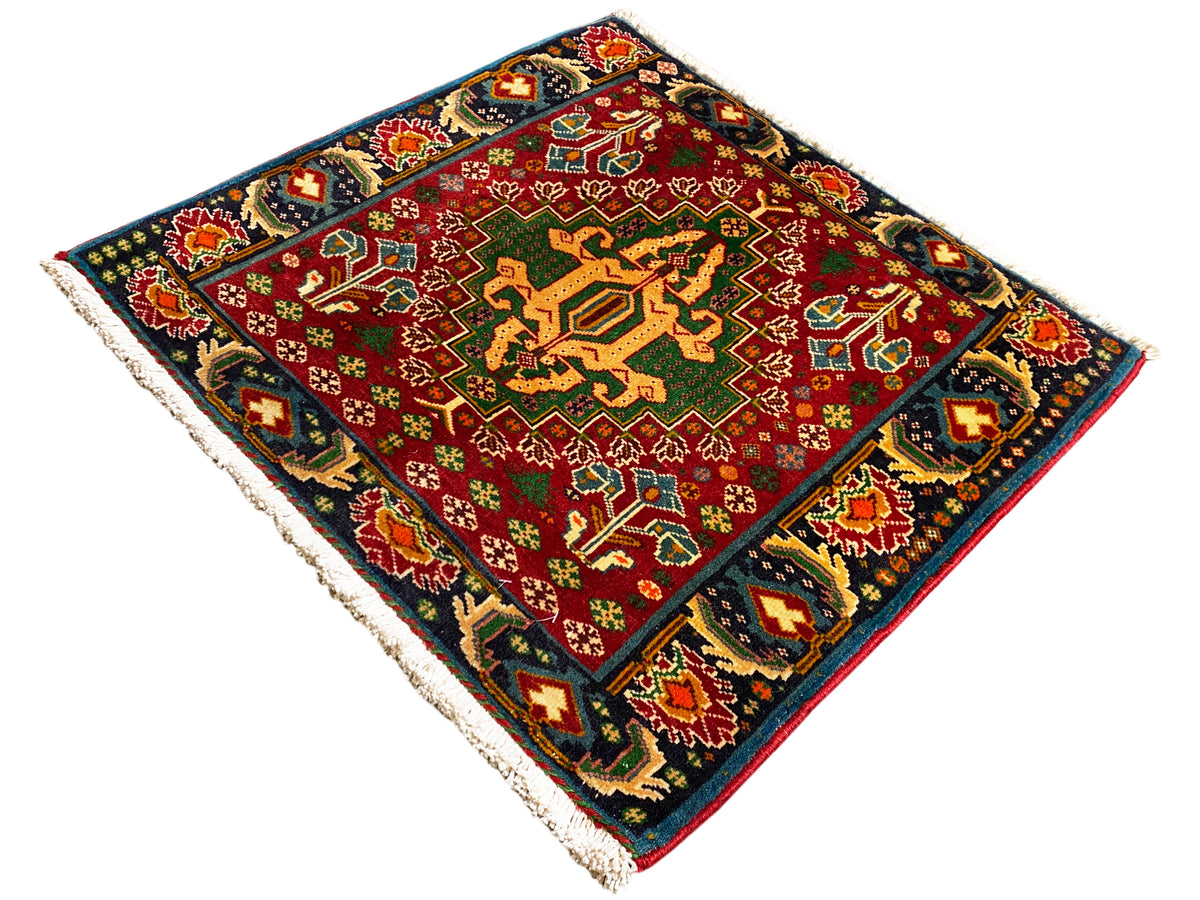 Tapete retangular (67x66 cm) com centro vermelho, borda escura e ornamentos multicoloridos, franjas
