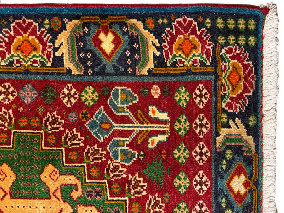 Tapete em grande detalhe: ornamentos coloridos sobre fundo escuro, motivos vermelhos e verdes, borda tecida