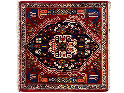 Tapete retangular com moldura vermelha, campo interior azul-escuro e padrão geométrico