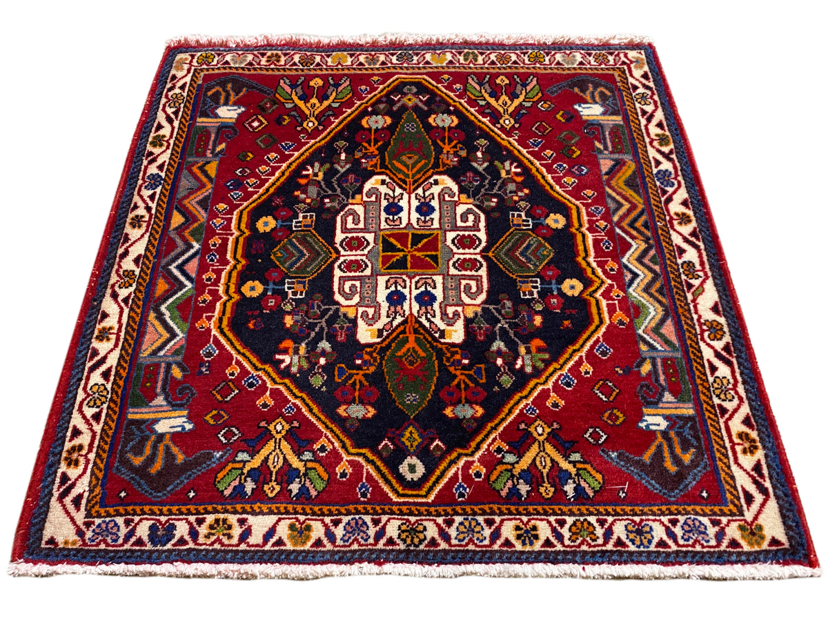 Tapete Poshti (67×67 cm) em perspetiva oblíqua: cercadura, centro vermelho, azul escuro
