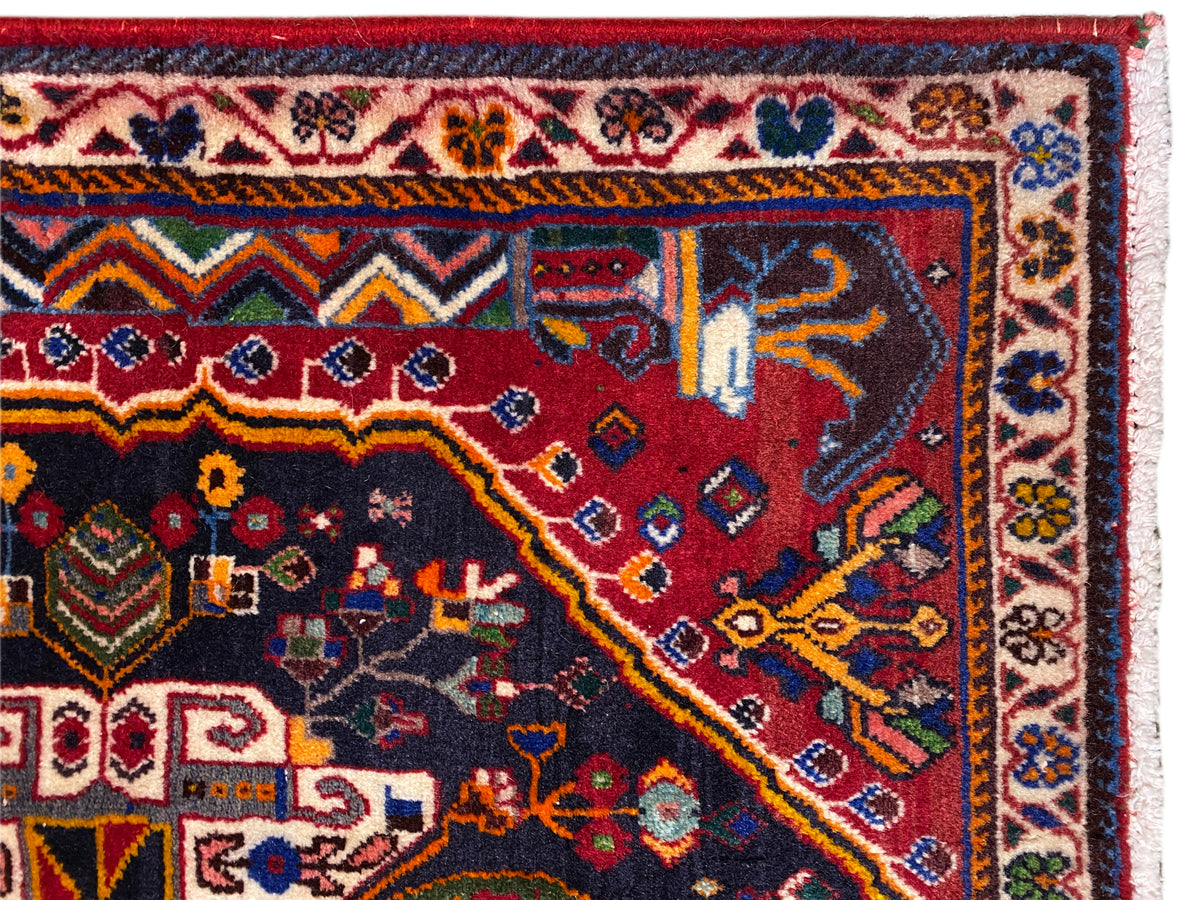 Borda de tapete com cercadura decorativa, padrão vermelho e azul e franjas brancas, vista detalhada