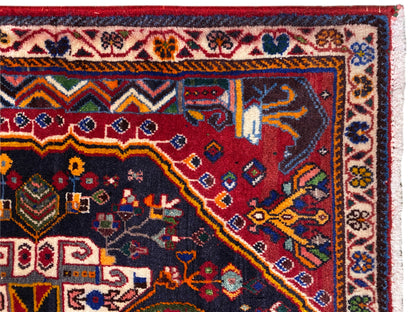 Borda de tapete com cercadura decorativa, padrão vermelho e azul e franjas brancas, vista detalhada