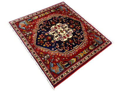 Tapete Poshti 65x61 cm, vista diagonal: campo vermelho com padrão escuro e ornamentos nas extremidades