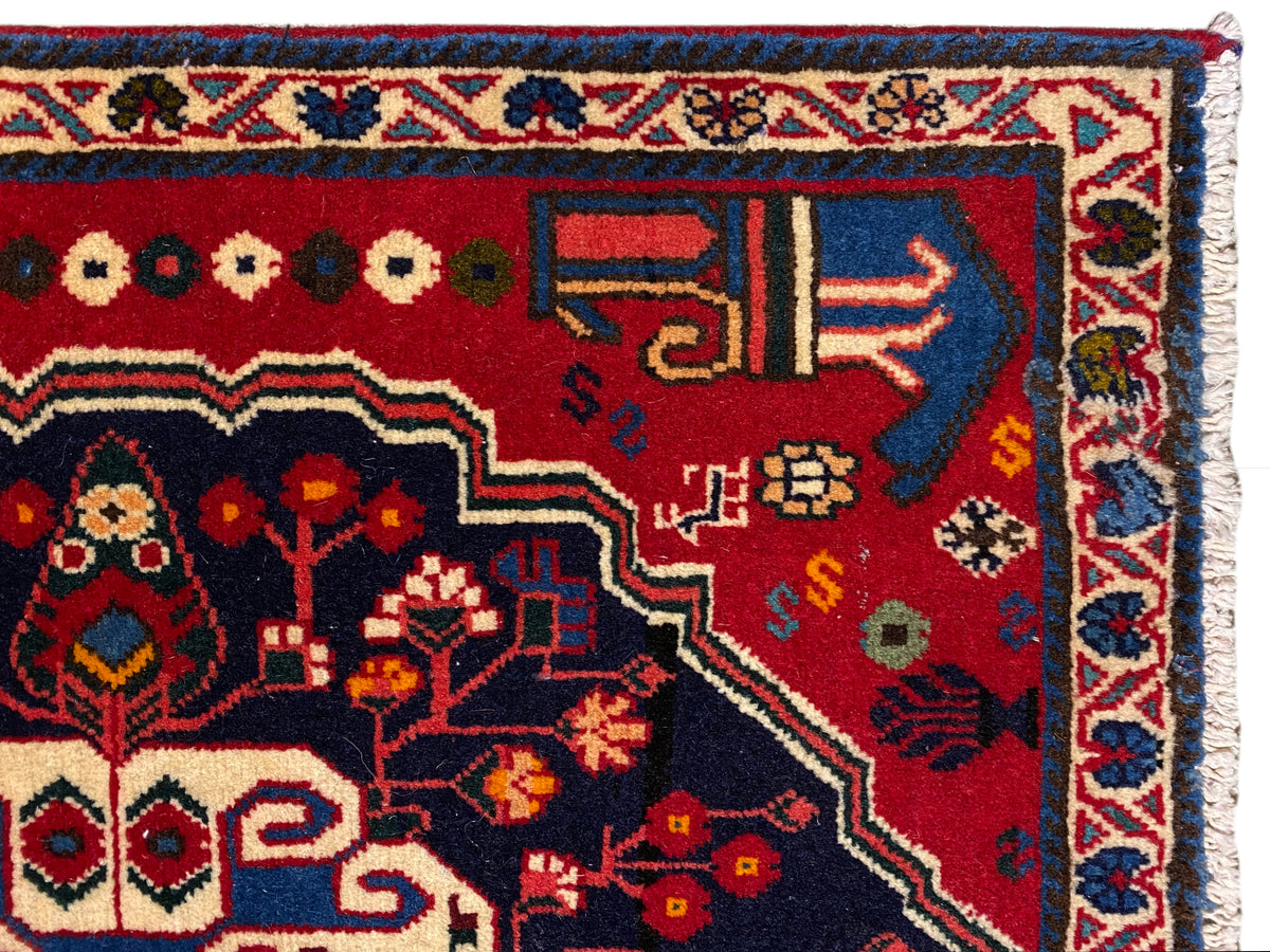 Canto de tapete com fundo vermelho, símbolos coloridos e moldura decorativa azul