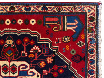 Canto de tapete com fundo vermelho, símbolos coloridos e moldura decorativa azul